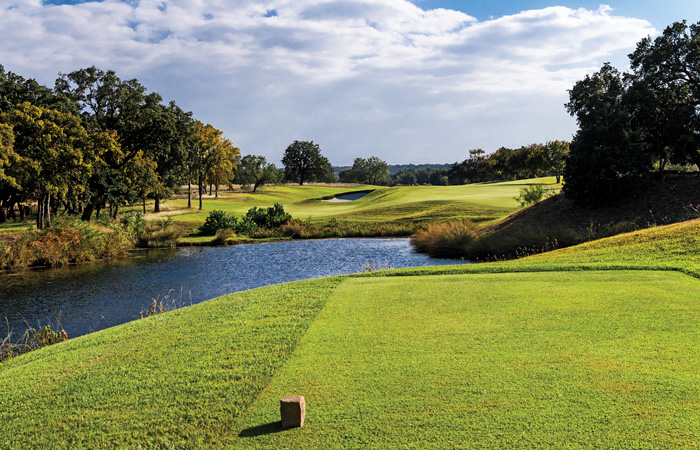 Golf course green with bunker, tee green, and lake