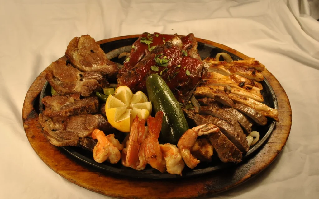 A fajita with steak, pork, shrimp, vegetables, peppers, and a lemon