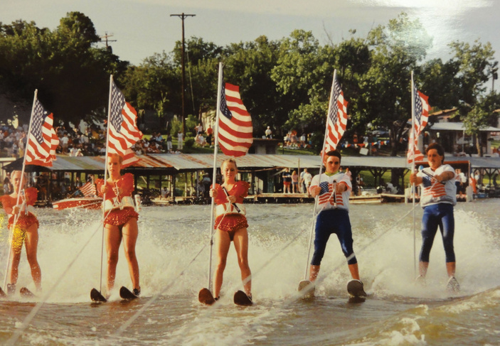 a set of 5 water skiers with American flags on a lake