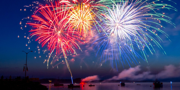Red, yellow, gree, white, and blue fireworks over Lake LBJ with boats in the water.