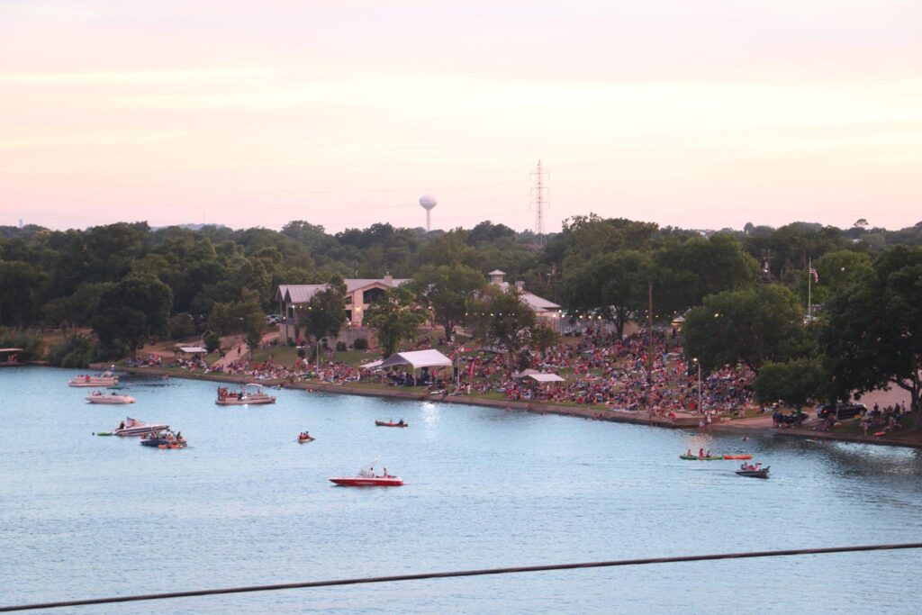 An image overlooking Lake Marble Falls. There are boats in the water and people on the bank.