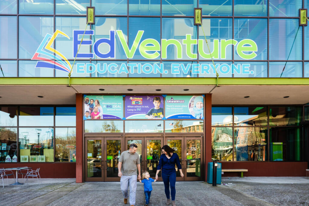 a mother, father, and child walking out of a building that says EdVenture Education and Everyone