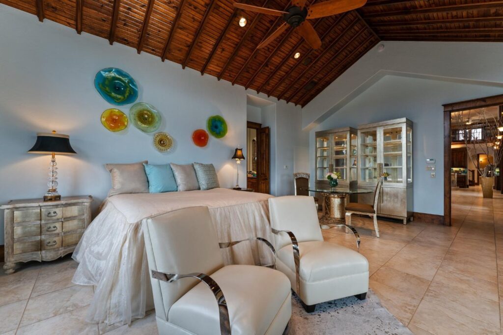 a tile floor bedroom with chairs, a table, and a nightstand