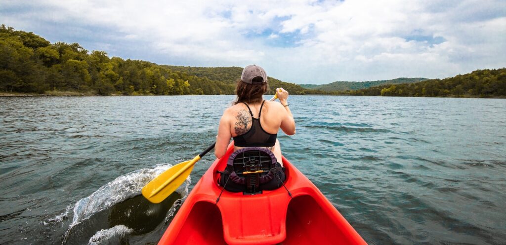 Woman in a Kayak on a Lake; treese and hills in the background
