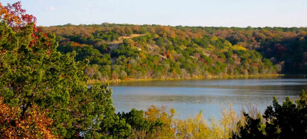A lake and green, orange, red, and yellow trees.