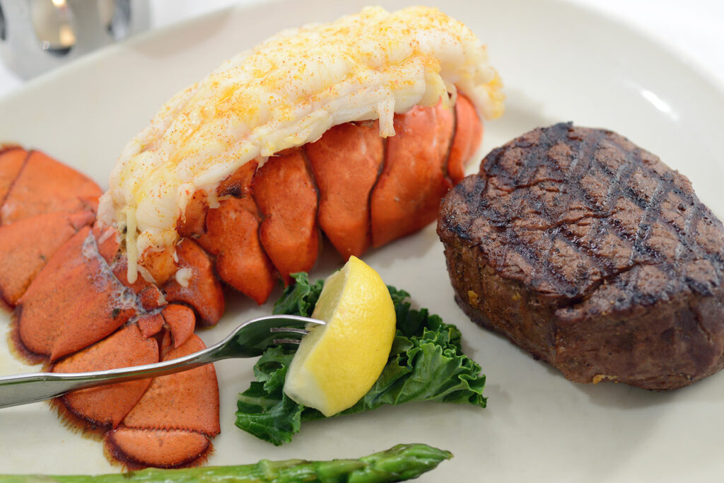A charred steak with stuffed lobster on a plate. 