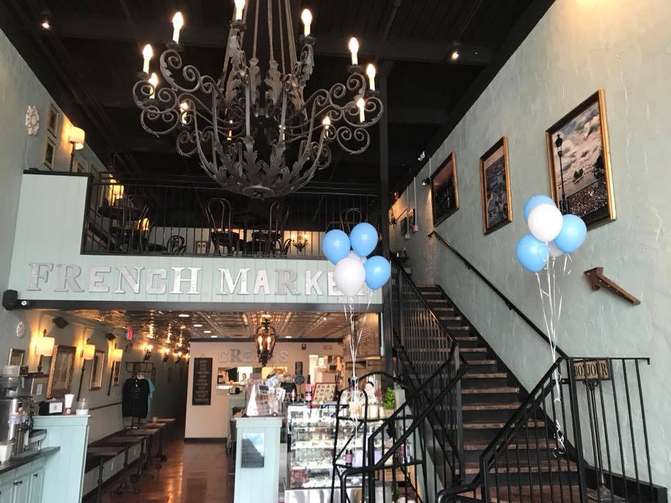 A chandelier hanging with a staircase and ordering counter in the background at the French Market Creperie in Farragut, TN. 