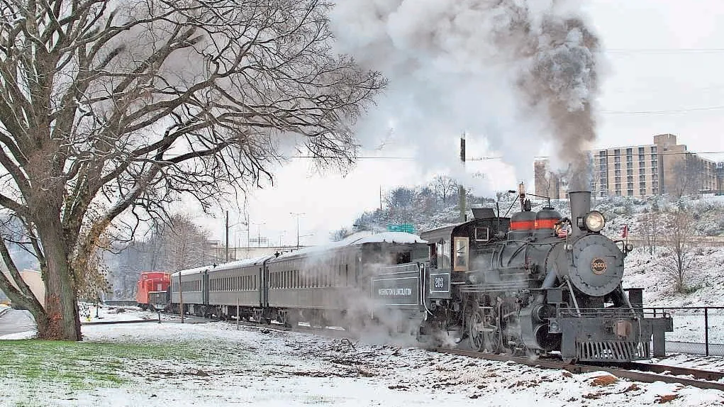 Train with smoke surrounded by snowy scenery that offers holiday rides through Knoxville.