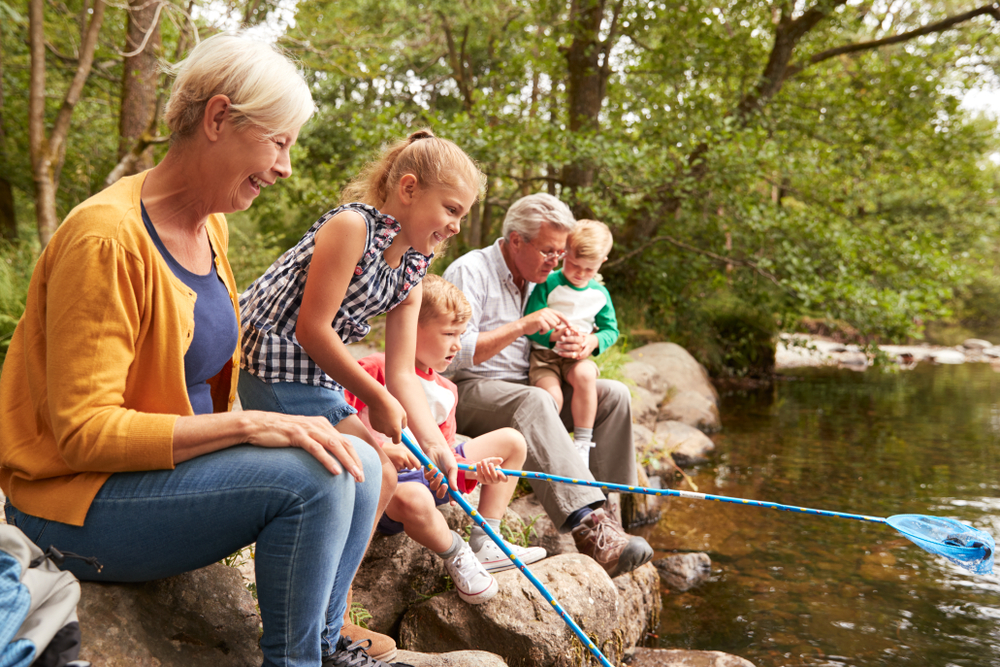 Older woman and man fish with three grandchildren at the lake.