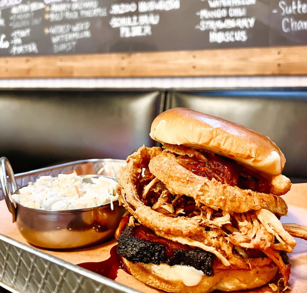 Hamburger with onions rings beside a dipping sauce.