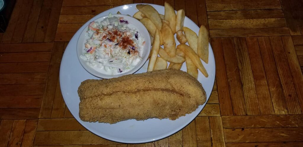 Fried fish beside french fries, and cole slaw.