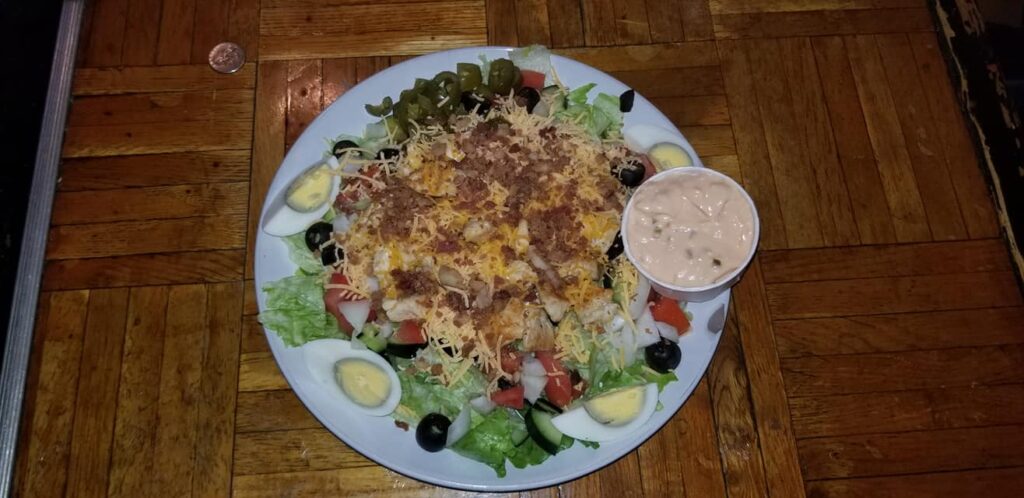 Salad with bacon, eggs, cheese, and veggies.