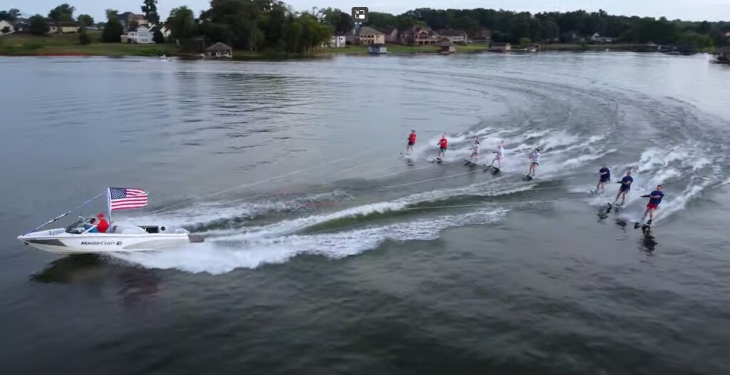 a group of water skiers behind a boat with an American flag