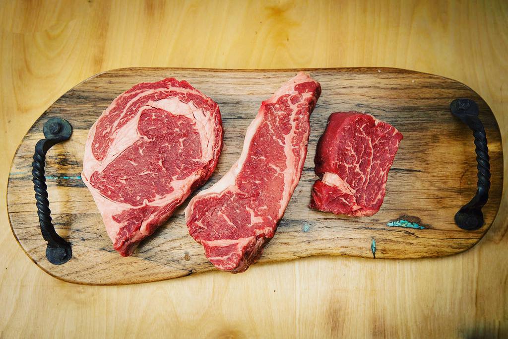 Three cuts of steak on top of a wooden board at Z Bar Cattle Co. in Argyle, Texas.