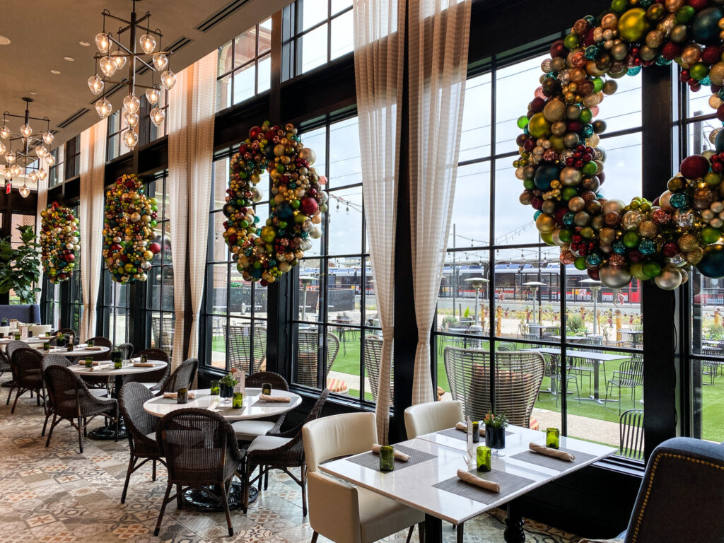 Wreaths made from ornaments over tables inside Bacchus Kitchen + Bar.