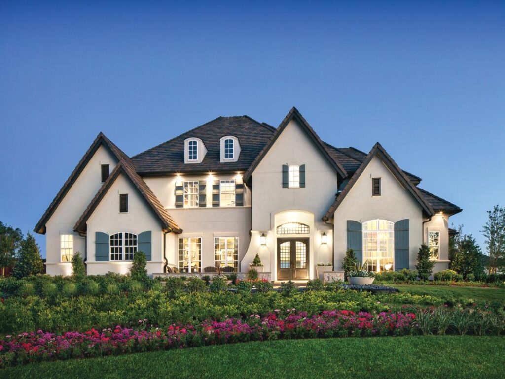 Large white home with flowers in front.