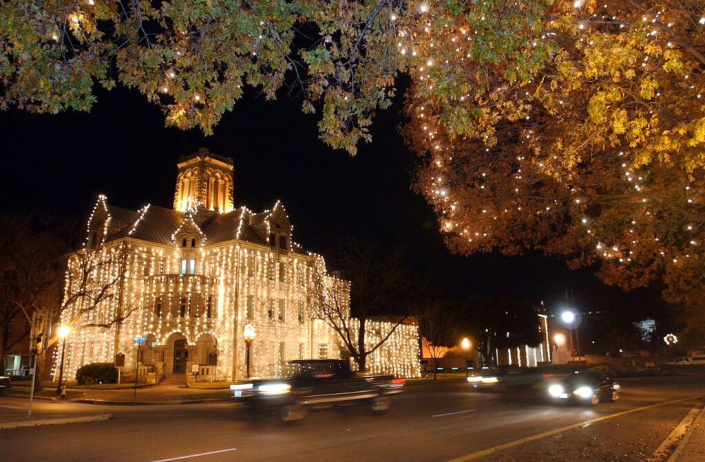 Downtown New Braunfels decorated with lights as cars pass by