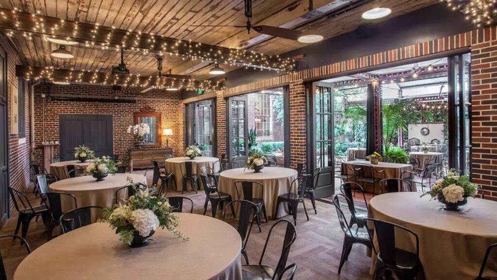 interior of a restaurant with tables, chairs, lights, and exposed brick