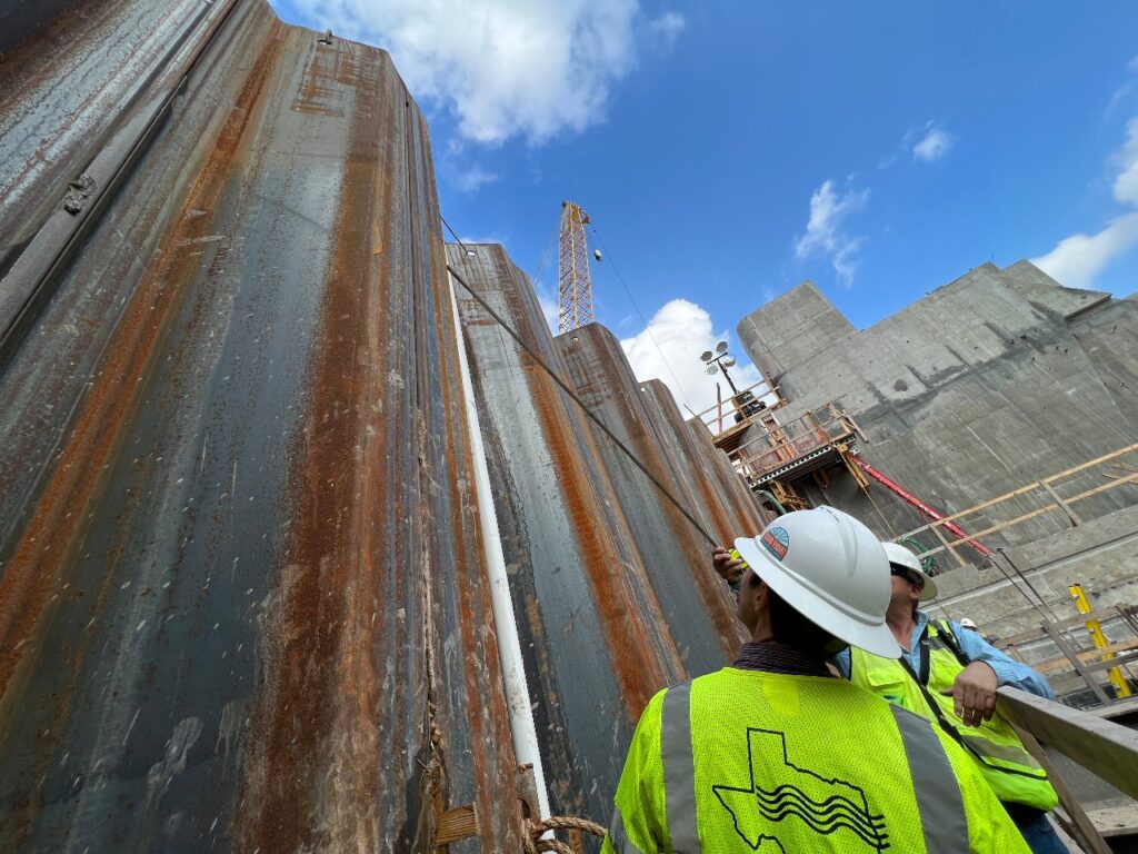 construction workers from GBRA looking at metal wall