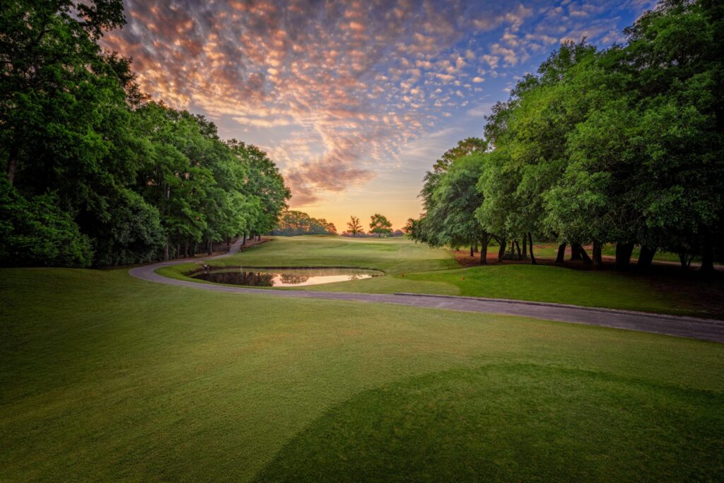 Santee National, featuring green grass, a small pond, luscious trees, and a breathtaking sunset.