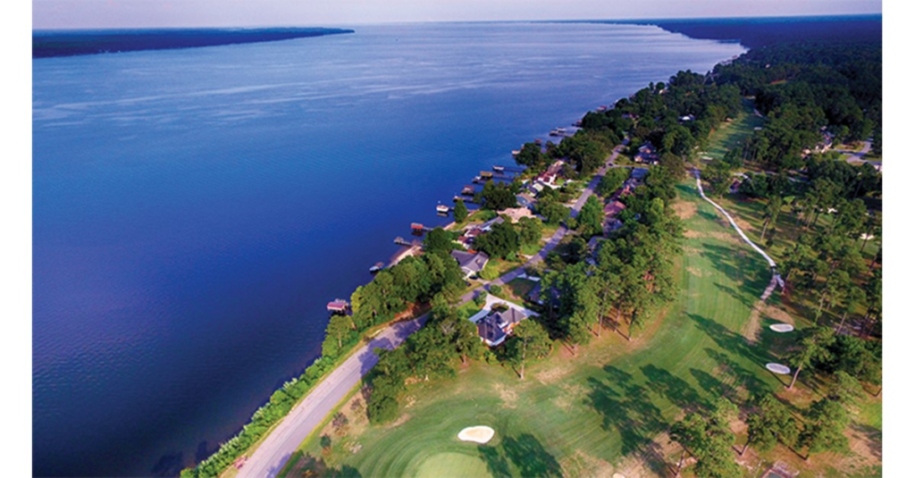 Santee Cooper Country Club, featuring a course with well-kept grass by houses and the massive blue Lake Marion.
