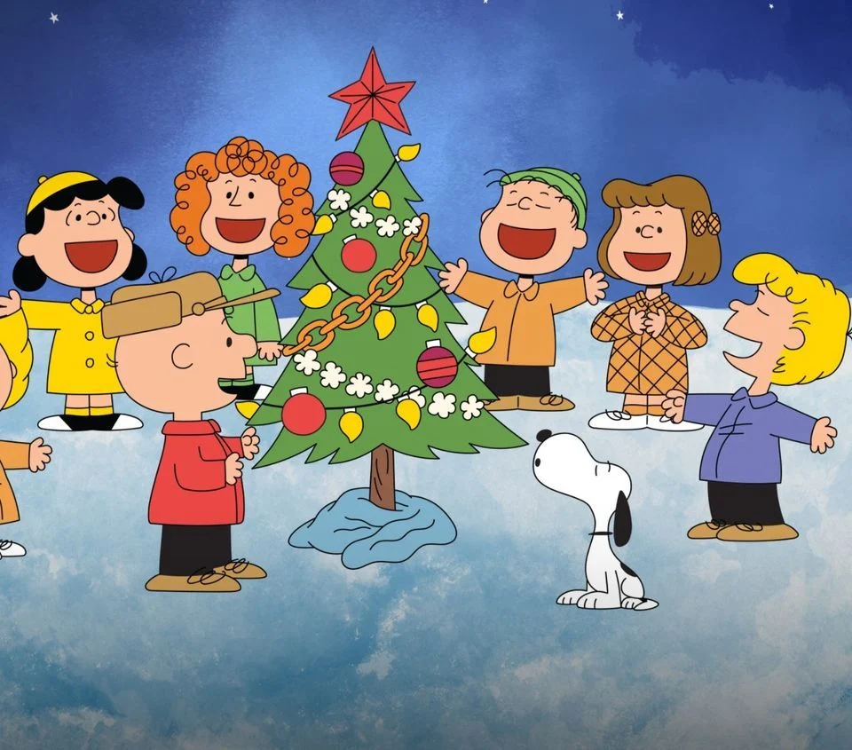 Charlie Brown characters gathered around a Christmas tree. 