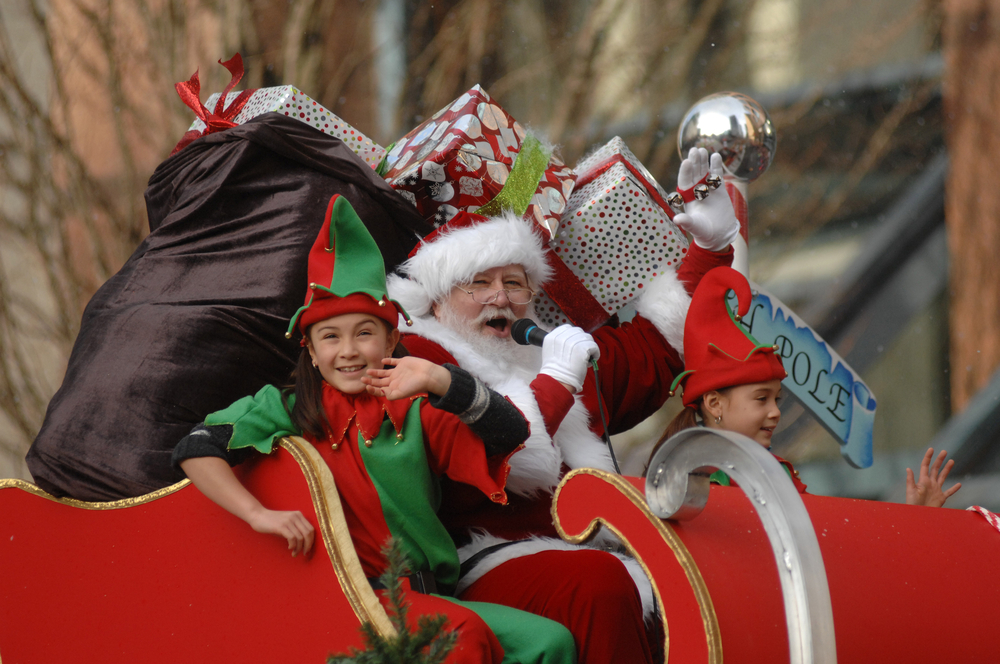 Santa and children dressed up as elves on a Christmas parade float. 