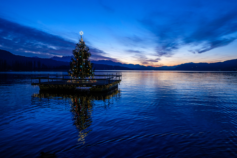 Christmas tree on pontoon in middle of lake. 